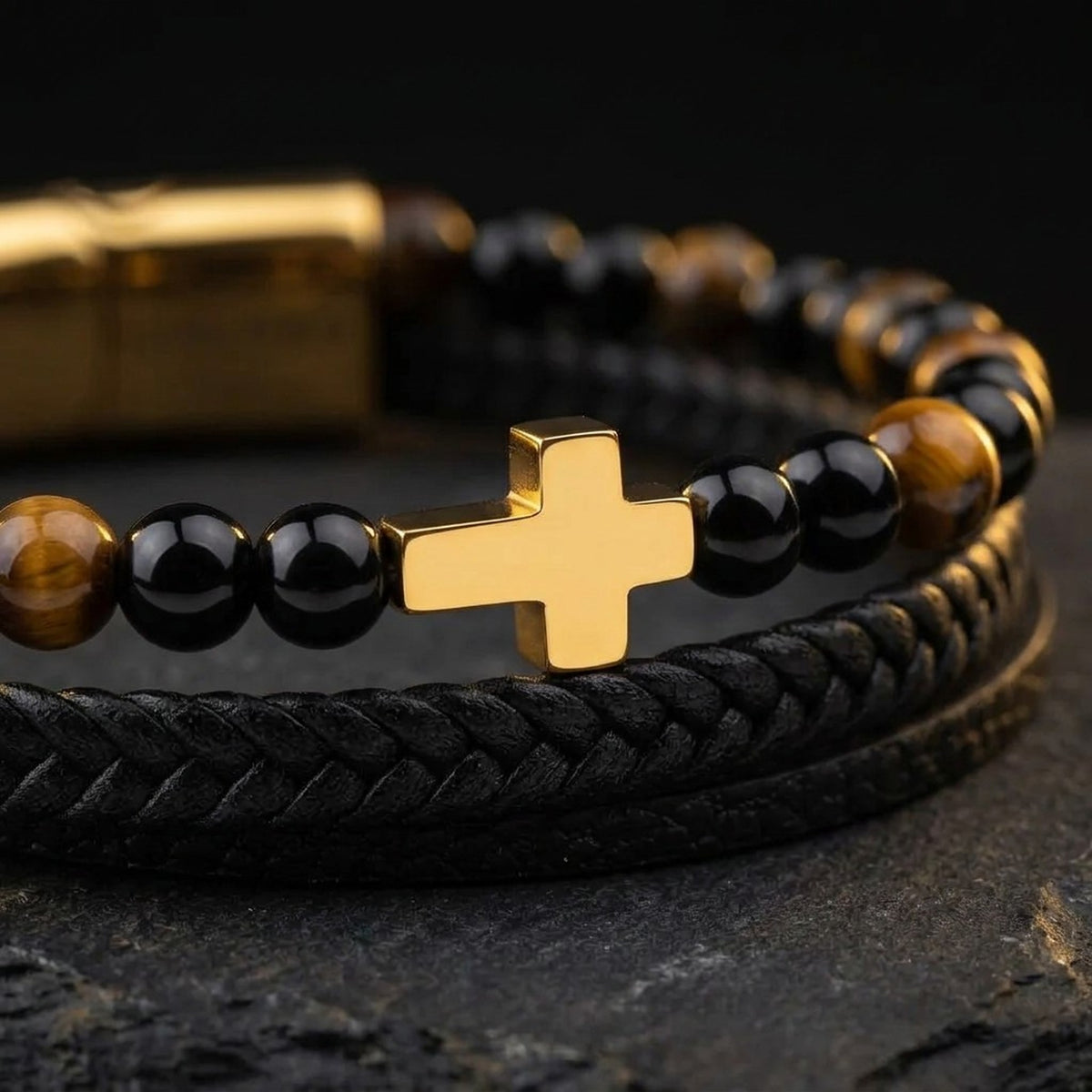 Close-up of the gold-tone cross, tiger eye beads and black braided leather on the men's cross bracelet