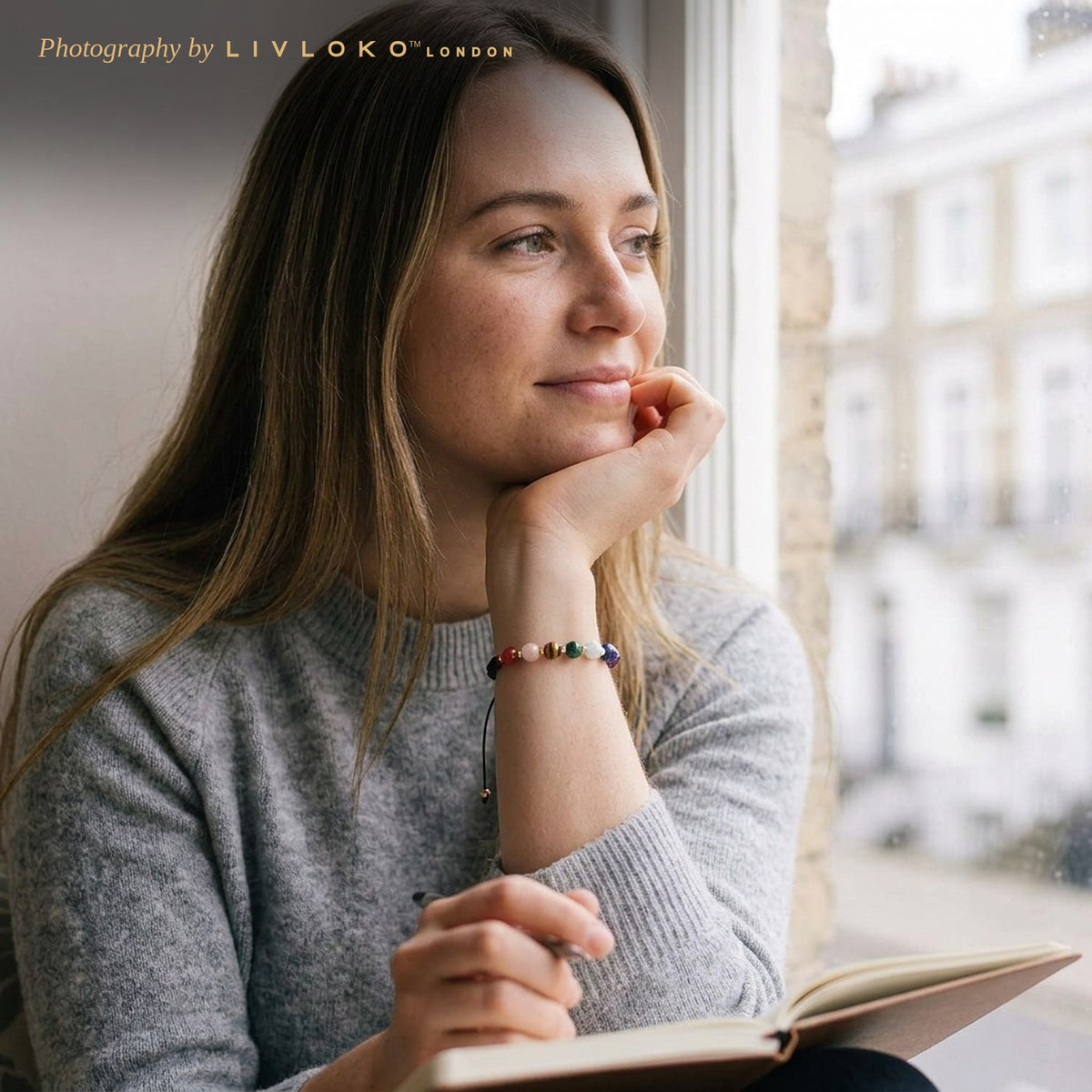 Woman journalling by a London window wearing the Livloko London chakra crystal cord bracelet