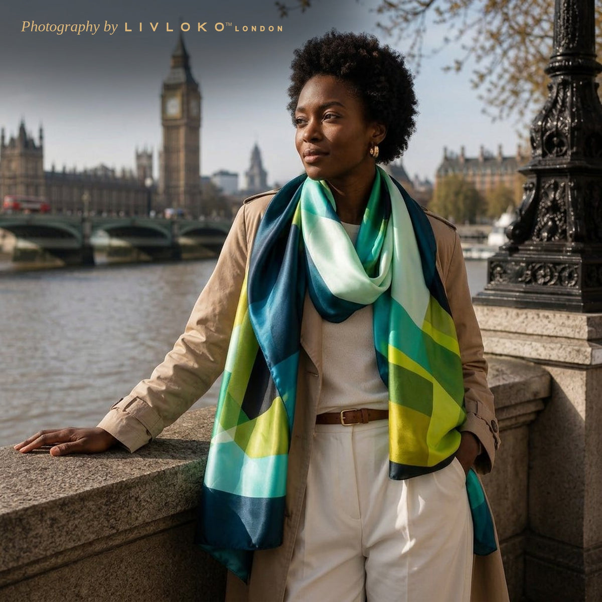 Woman wearing the green and yellow geometric satin scarf by the Thames in London