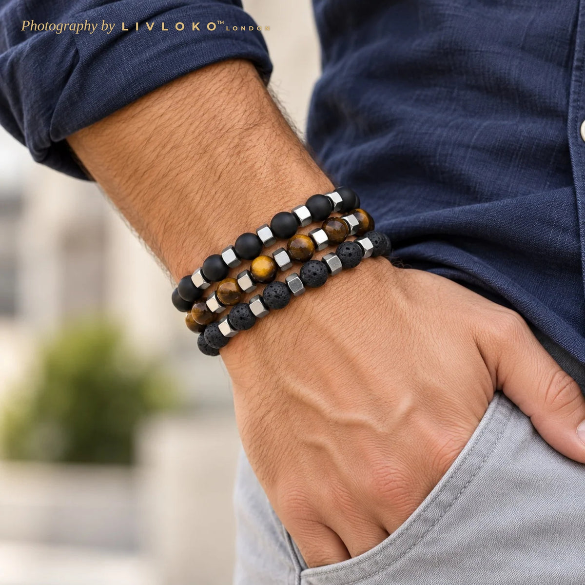 Men's beaded bracelet stack of matte black agate, tiger eye and lava stone with metal accents worn on the wrist