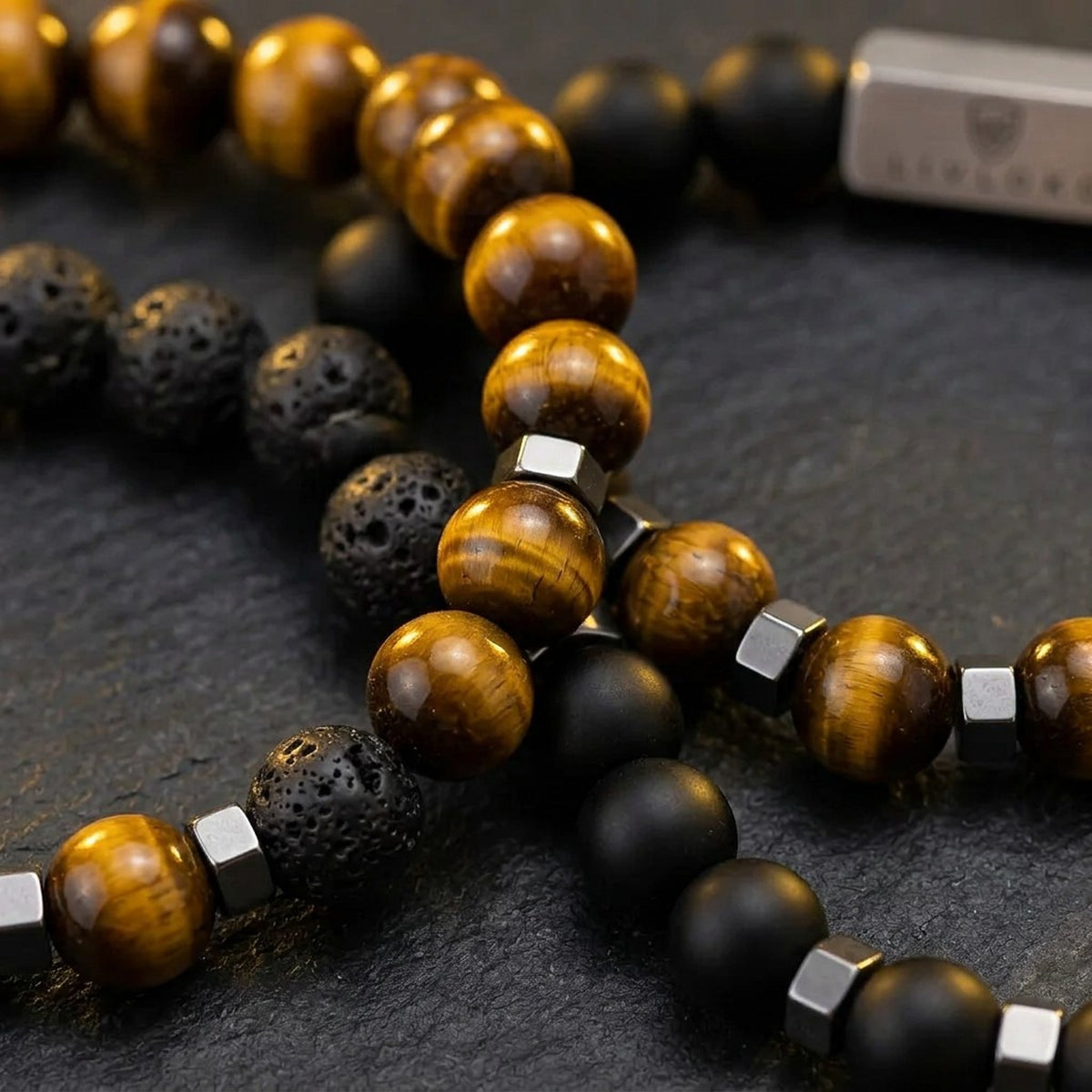 Close-up of the black and brown beads with metal accent details on the men's bracelet stack