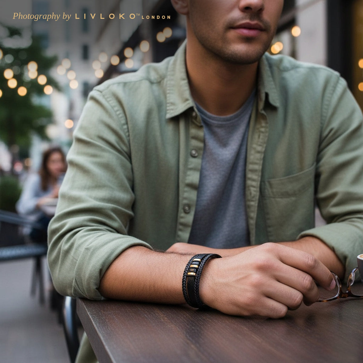 Man wearing the men's black and gold leather bracelet at an outdoor cafe table