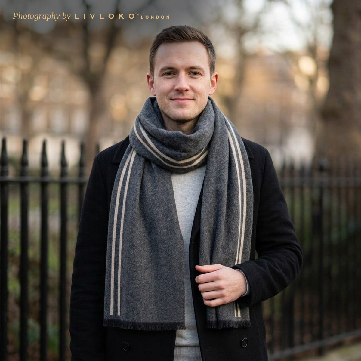 Man wearing the LIVLOKO London grey and beige striped wool scarf with a black peacoat