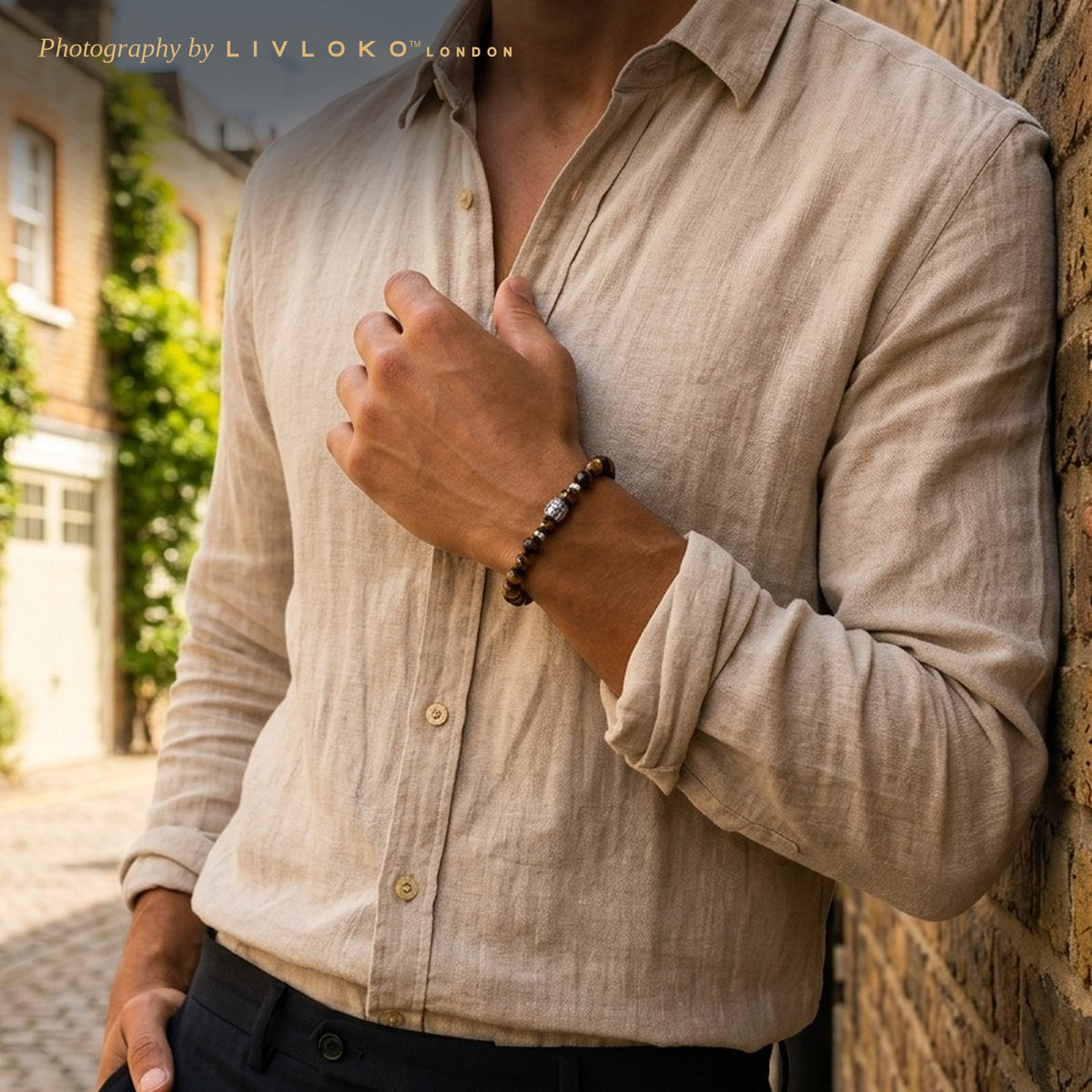 Man in a linen shirt wearing the men's tiger eye beaded bracelet with Buddha charm in a London mews