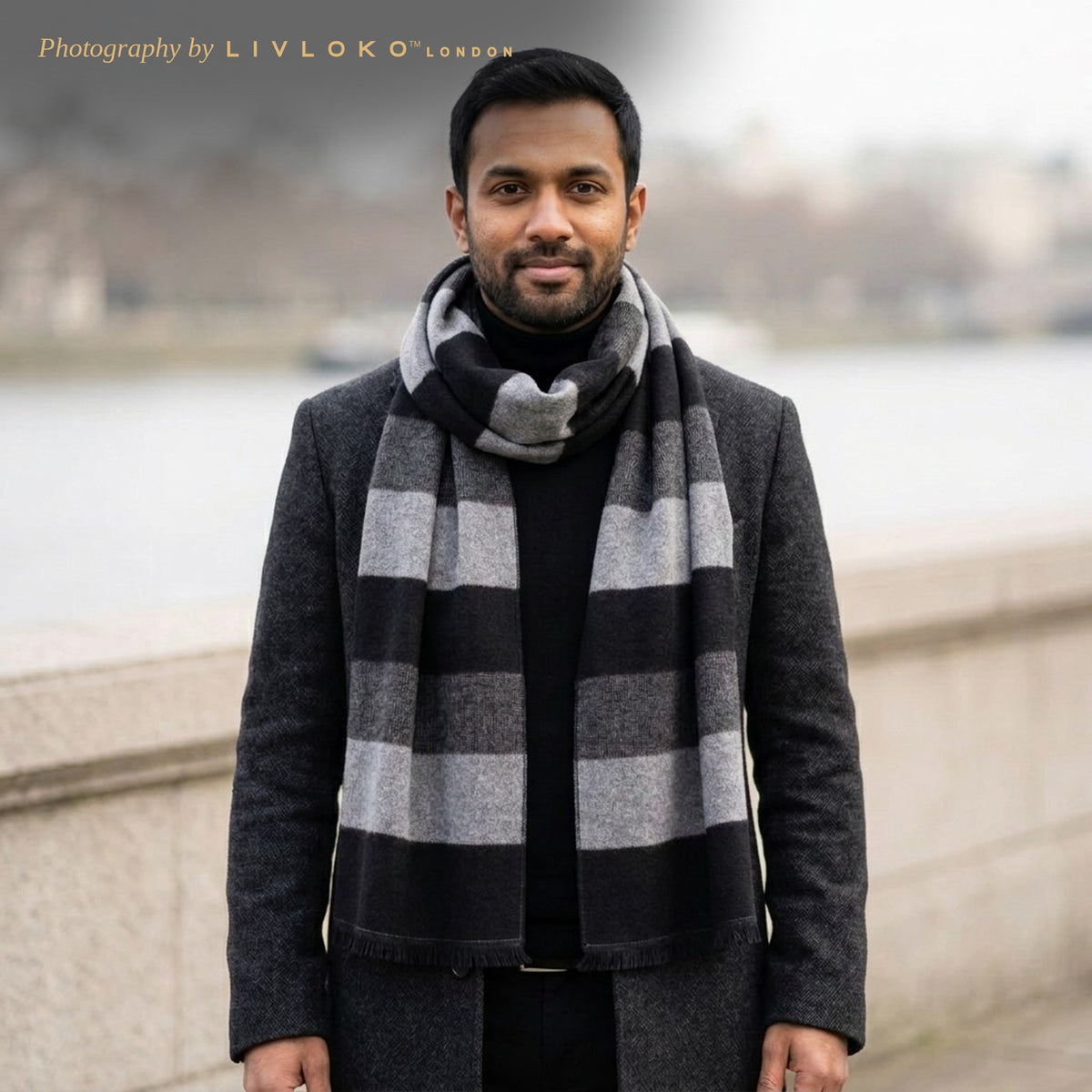 Man wearing the LIVLOKO London black and grey striped wool scarf with a charcoal overcoat