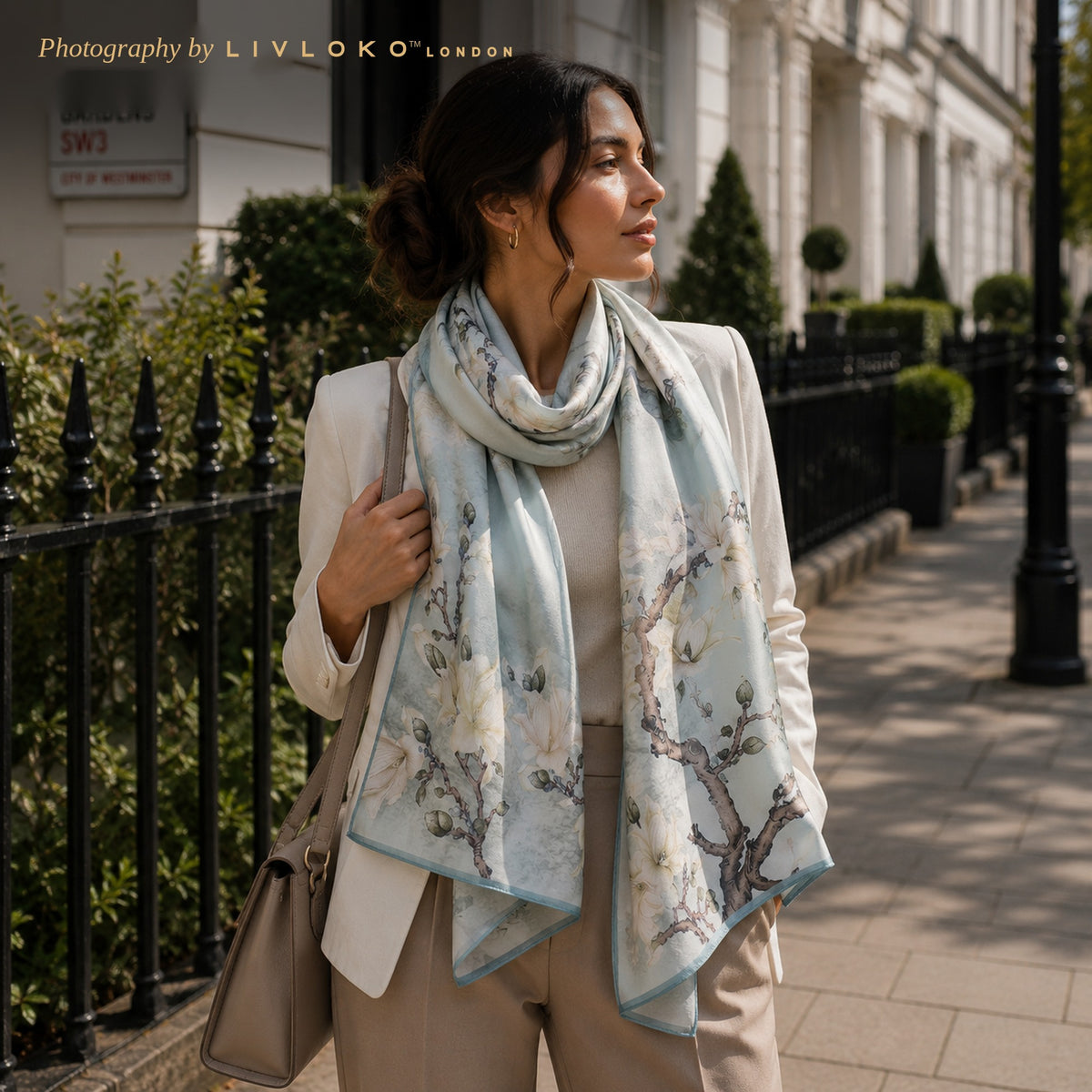 Woman wearing the Sky Blossom grey and cream mulberry silk scarf looped at the neck on a London street
