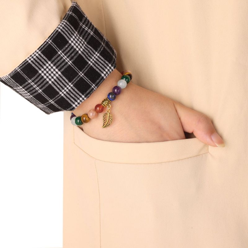 Gold-plated 7 Chara Braclet and Leaf Charm 7 Chakra Bracelet & Leaf Pendant around woman's wrist