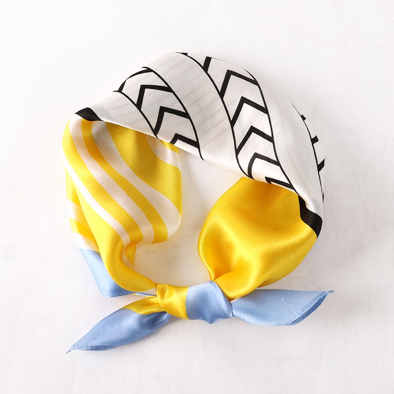 Scarf tied in a loop with a knot, showing yellow panels, black chevrons on cream and pale blue ends