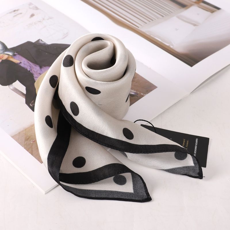Polka dot scarf rolled into a rosette on an open magazine, showing the black border