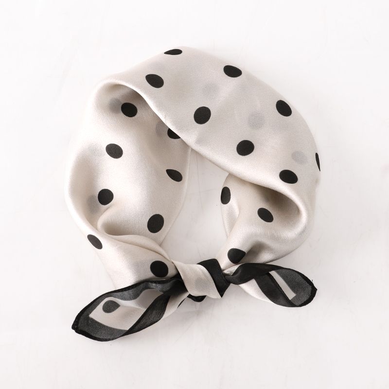 Ivory and black polka dot scarf tied into a loop with a knot, as worn as a neckerchief