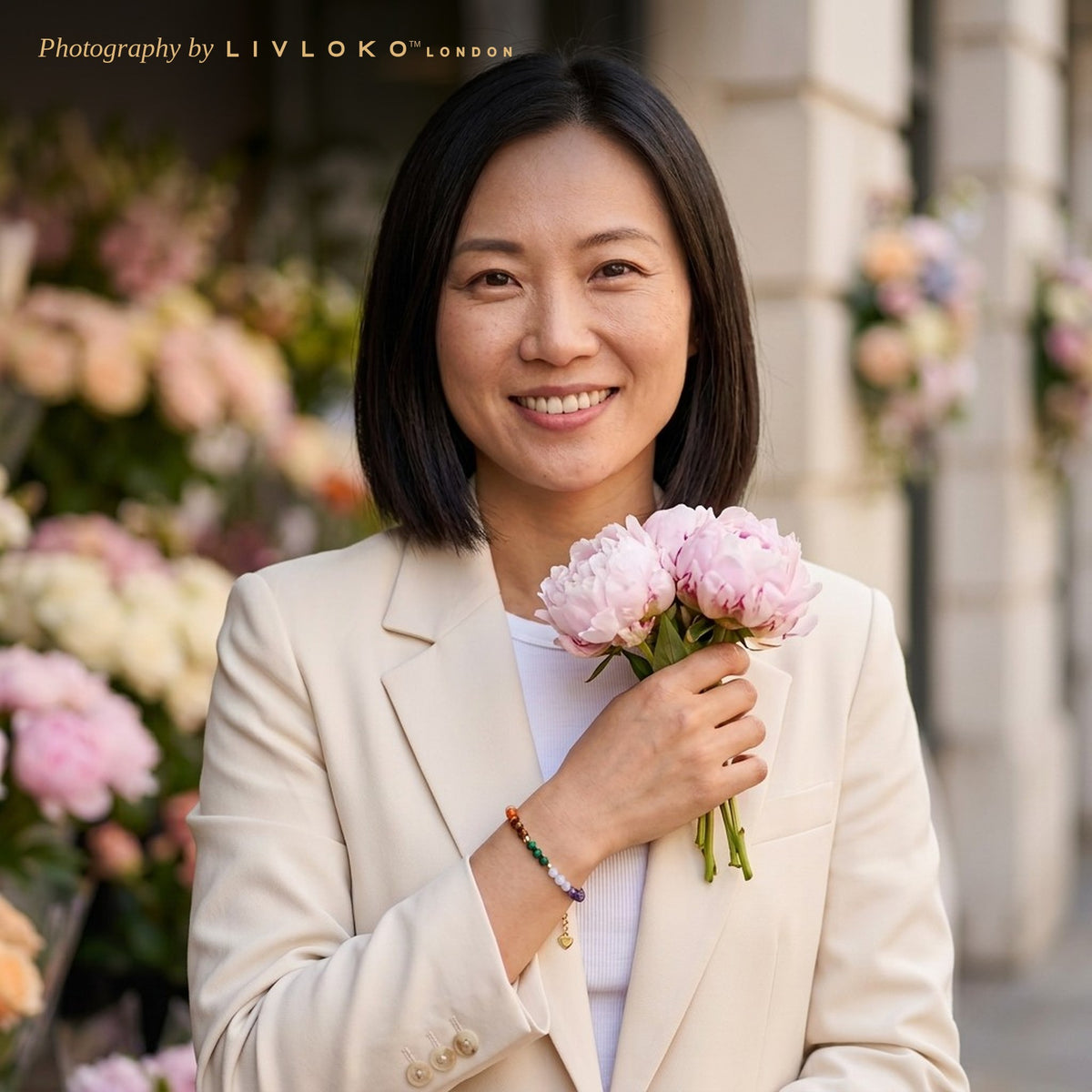 Woman holding peonies wearing the Livloko London gold plated tourmaline crystal bracelet at a London flower stall