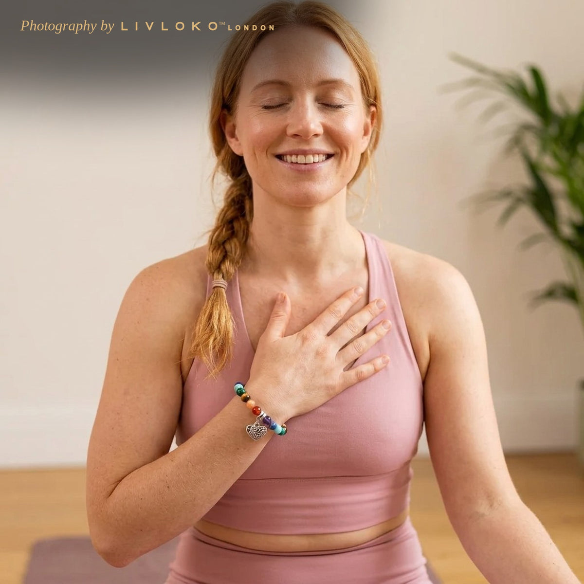 Woman in a yoga studio wearing the Livloko London 7 chakra bracelet with heart pendant
