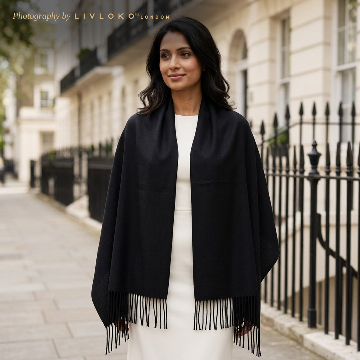 Woman wearing the black pashmina scarf as a wedding shawl over an ivory dress on a London street