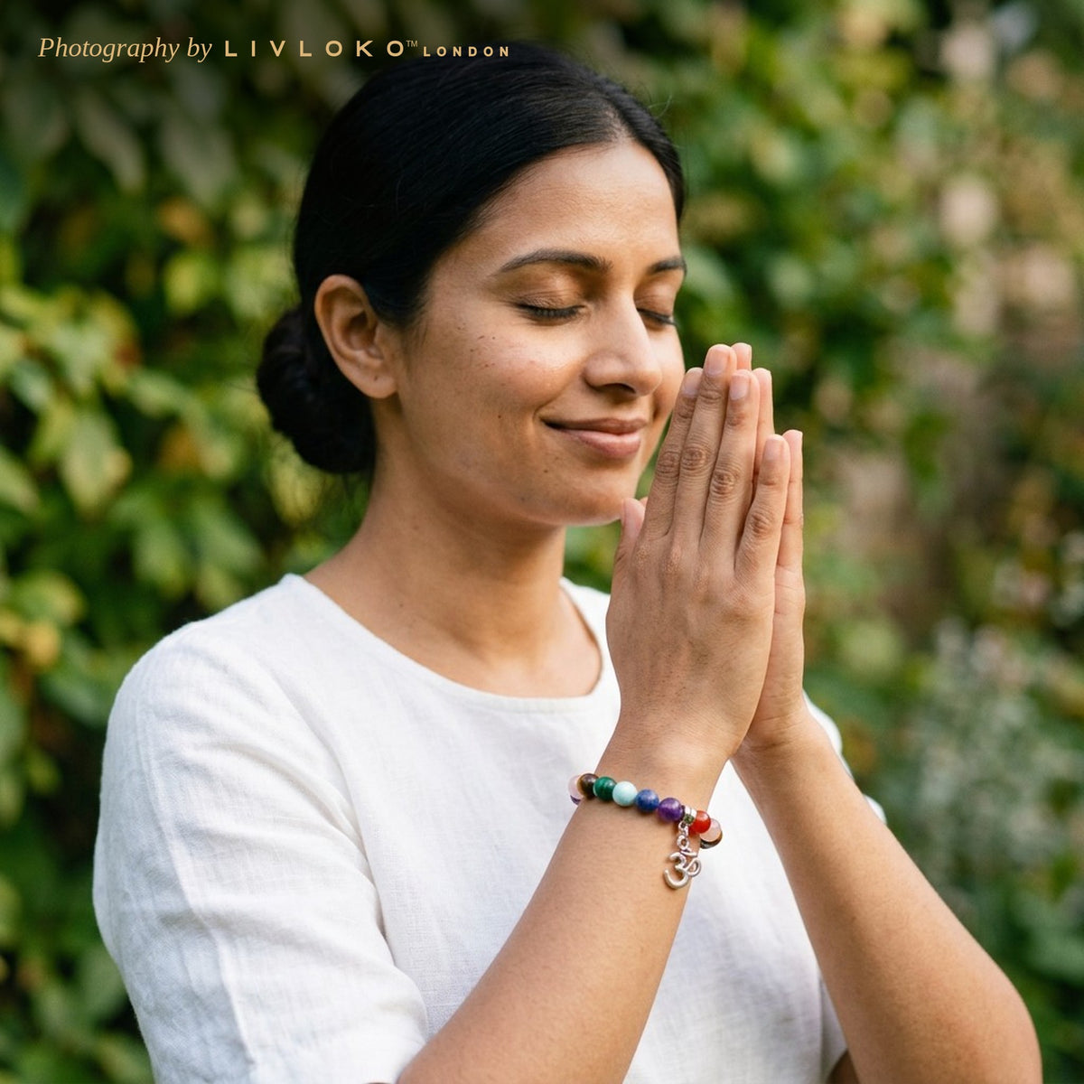 Woman in a garden wearing the Livloko London chakra crystal bracelet with Om pendant