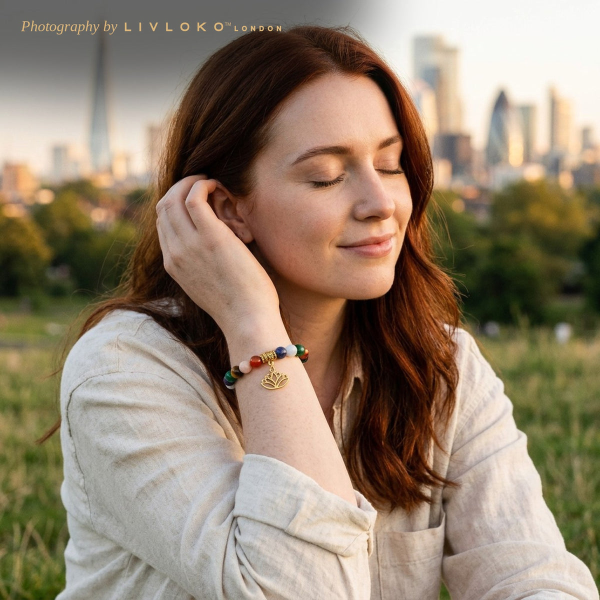 Woman wearing the Livloko London chakra stones bracelet with lotus charm on Primrose Hill with the London skyline behind