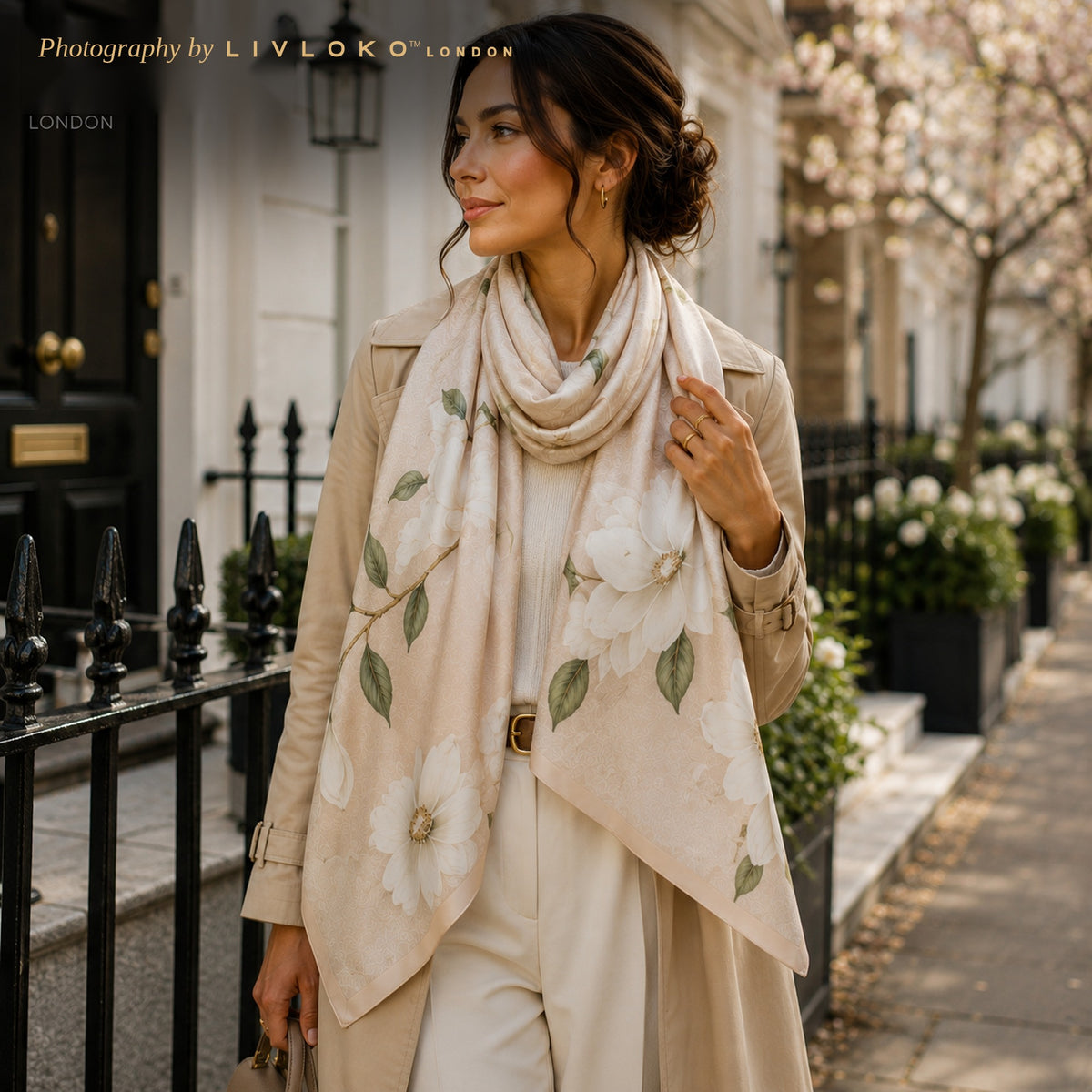 Woman wearing the Ivory Magnolia mulberry silk scarf draped as a lightweight wrap on a London street