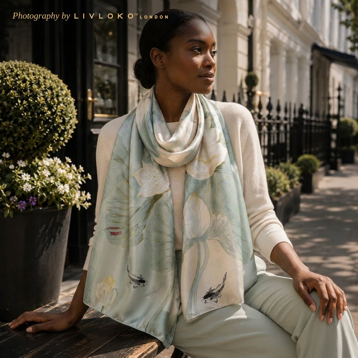 Woman wearing the Lotus Breeze sage green mulberry silk scarf loose over the shoulders in London