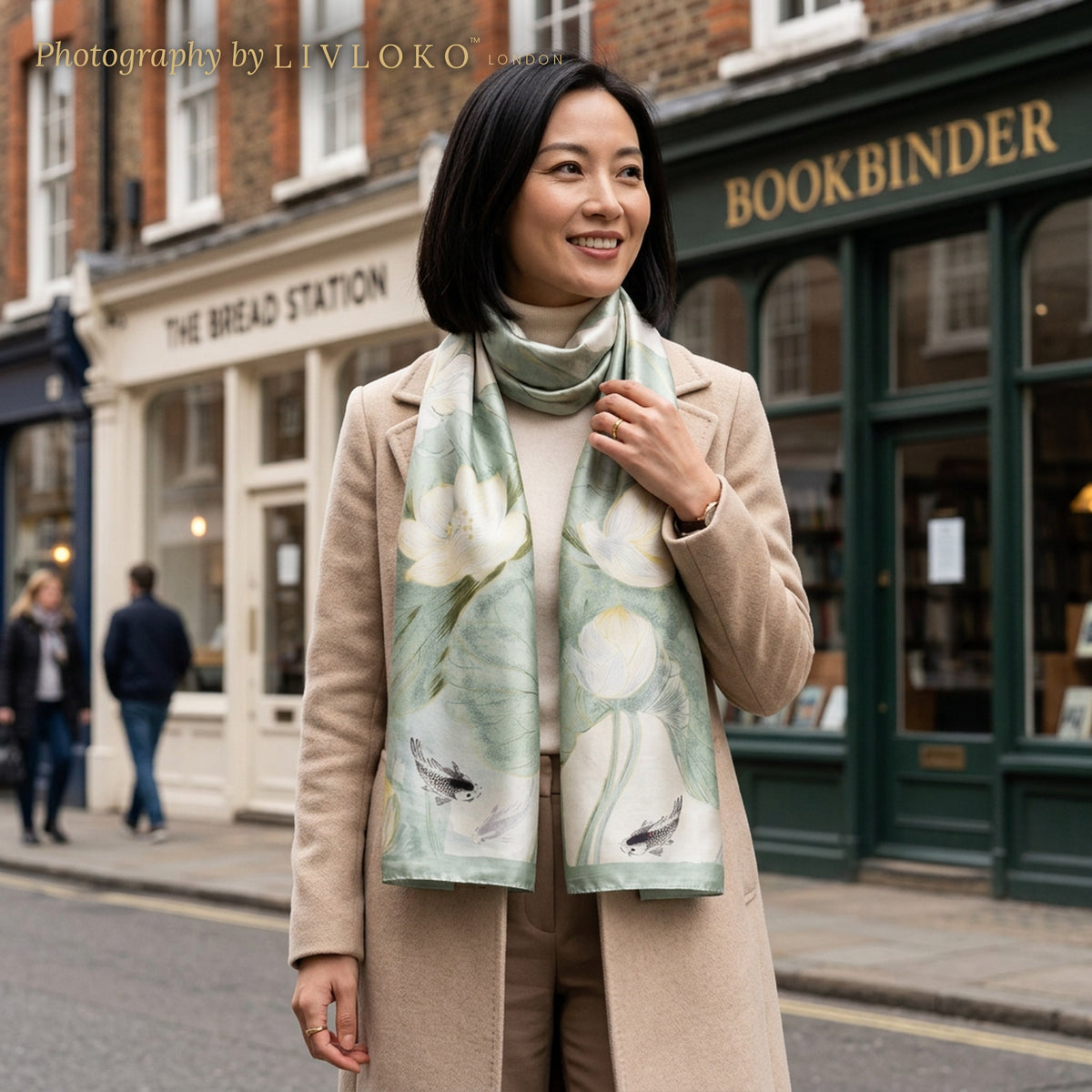 Woman wearing the Lotus Breeze sage green mulberry silk scarf on a London high street, LIVLOKO LONDON
