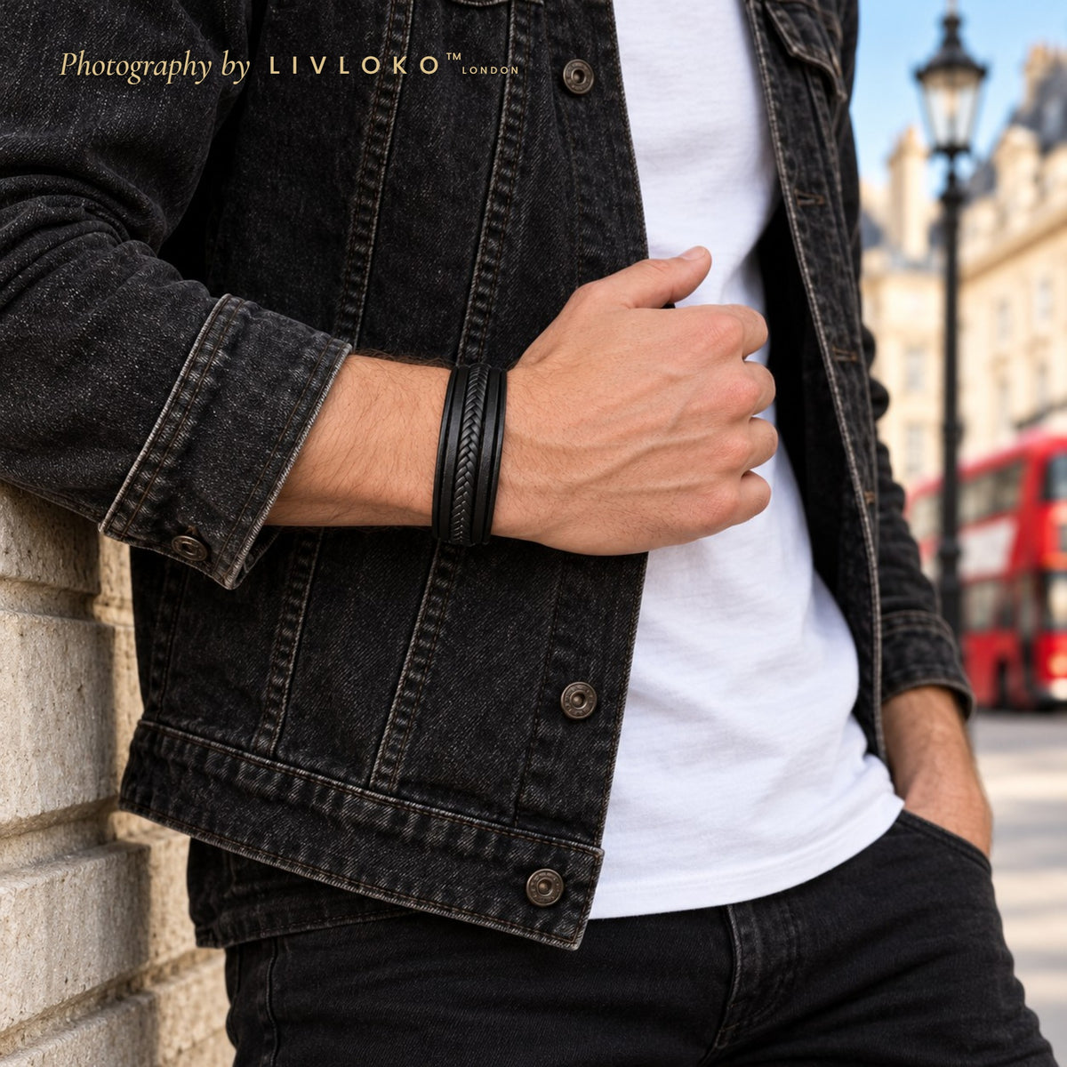 Men's black braided leather bracelet worn on the wrist with a black denim jacket in London