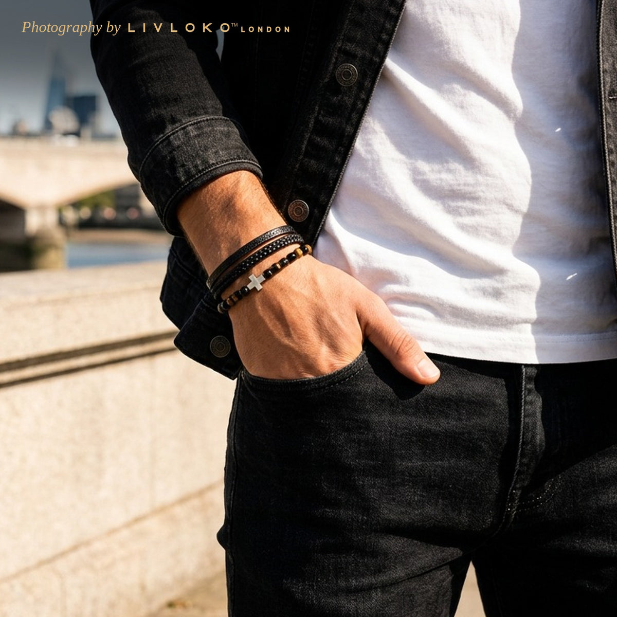 Man wearing the men's black leather cross bracelet with tiger eye beside the Thames in London