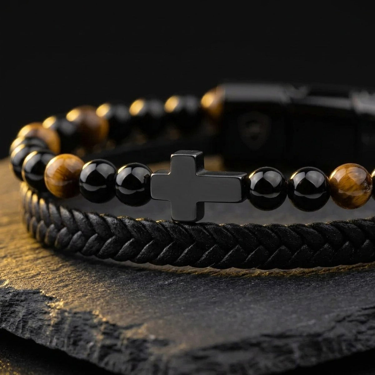 Close-up of the cross detail, tiger eye beads and black braided leather on the men's cross bracelet