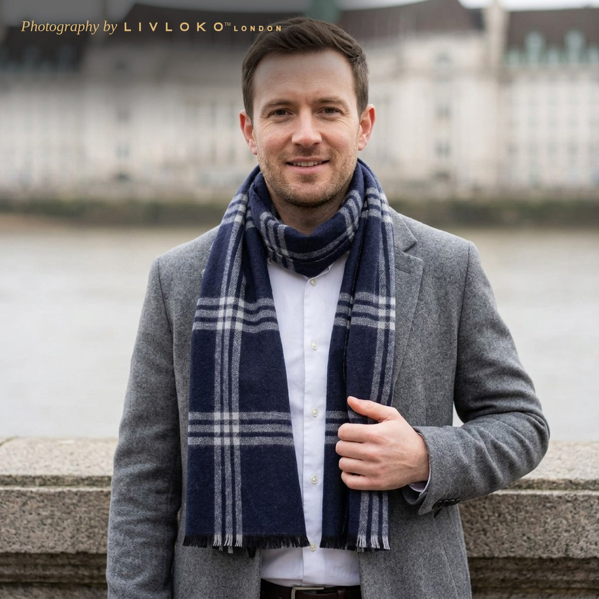 Man wearing the Livloko London men's blue and grey tartan wool scarf by the Thames in London