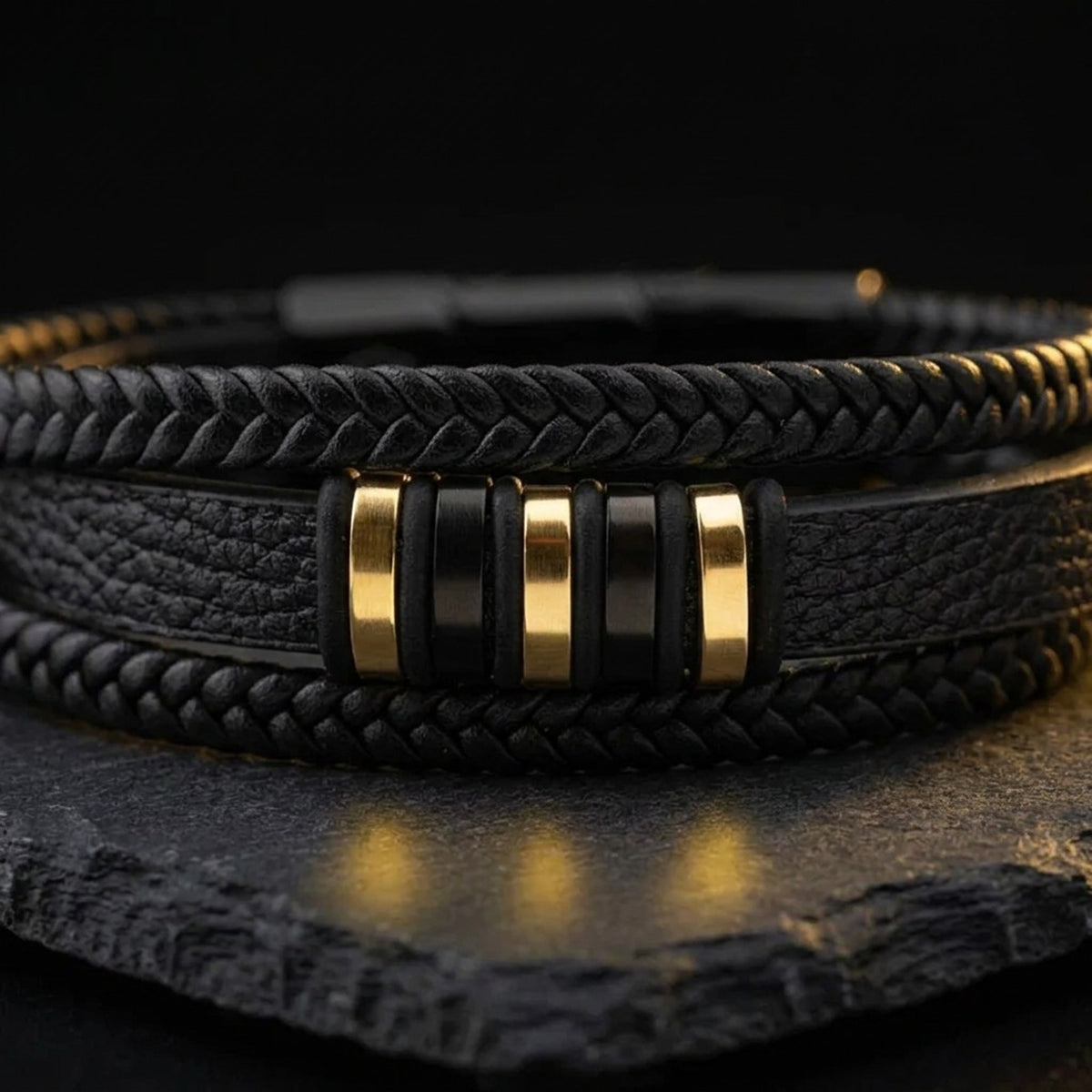 Close-up of the gold-tone details on the men's black leather and gold bracelet