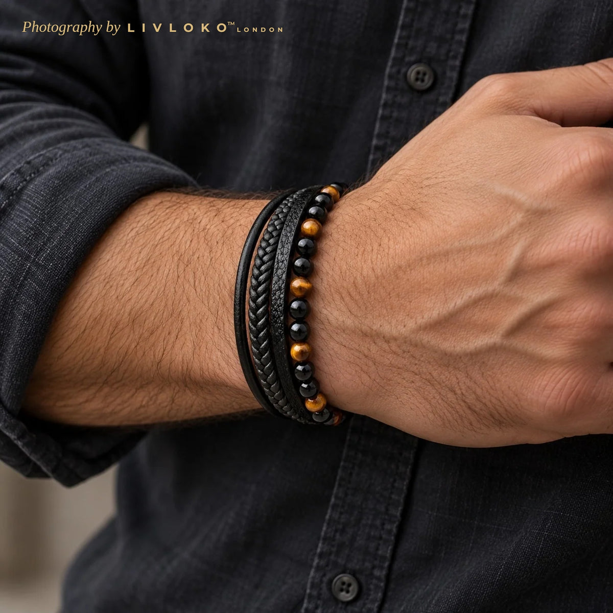 Men's tiger eye and black agate leather bracelet worn on the wrist with a charcoal denim shirt