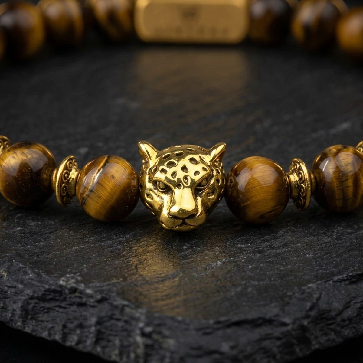Close-up of the gold tone leopard charm and tiger eye stone beads on the men's brown tiger eye bracelet