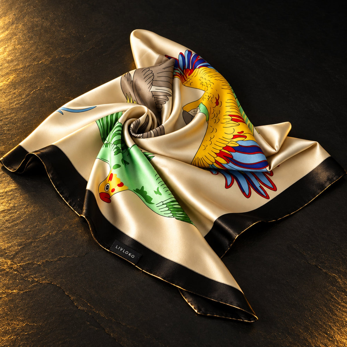 Parrot print satin scarf in cream with a black border, swirled on dark slate