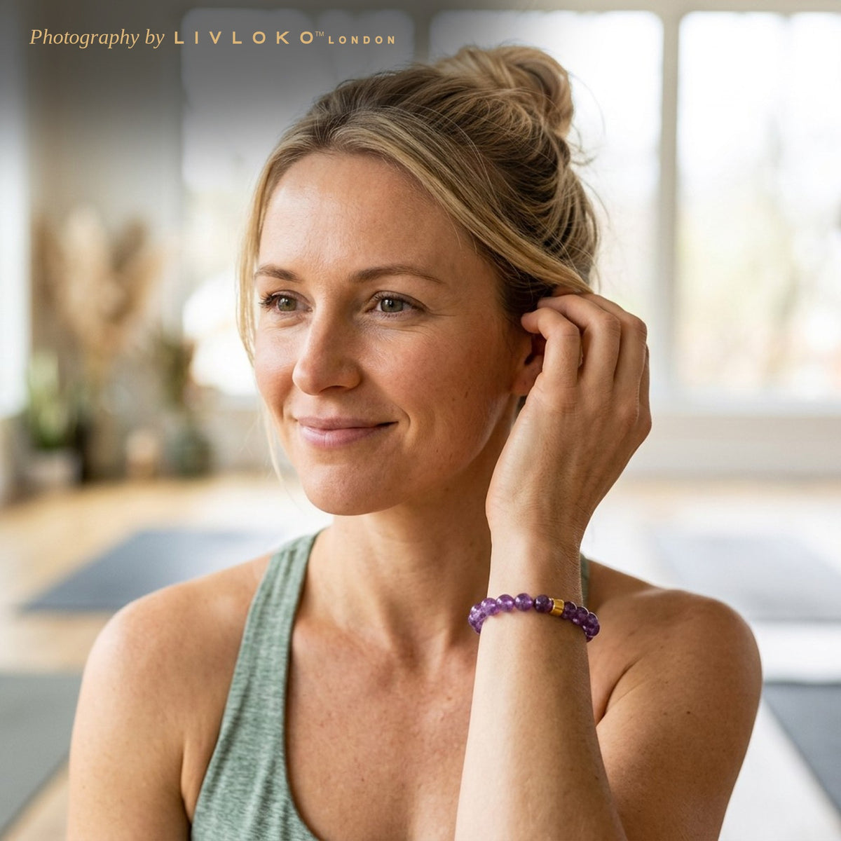 Woman in a yoga top wearing the Livloko London amethyst bead bracelet in a yoga studio