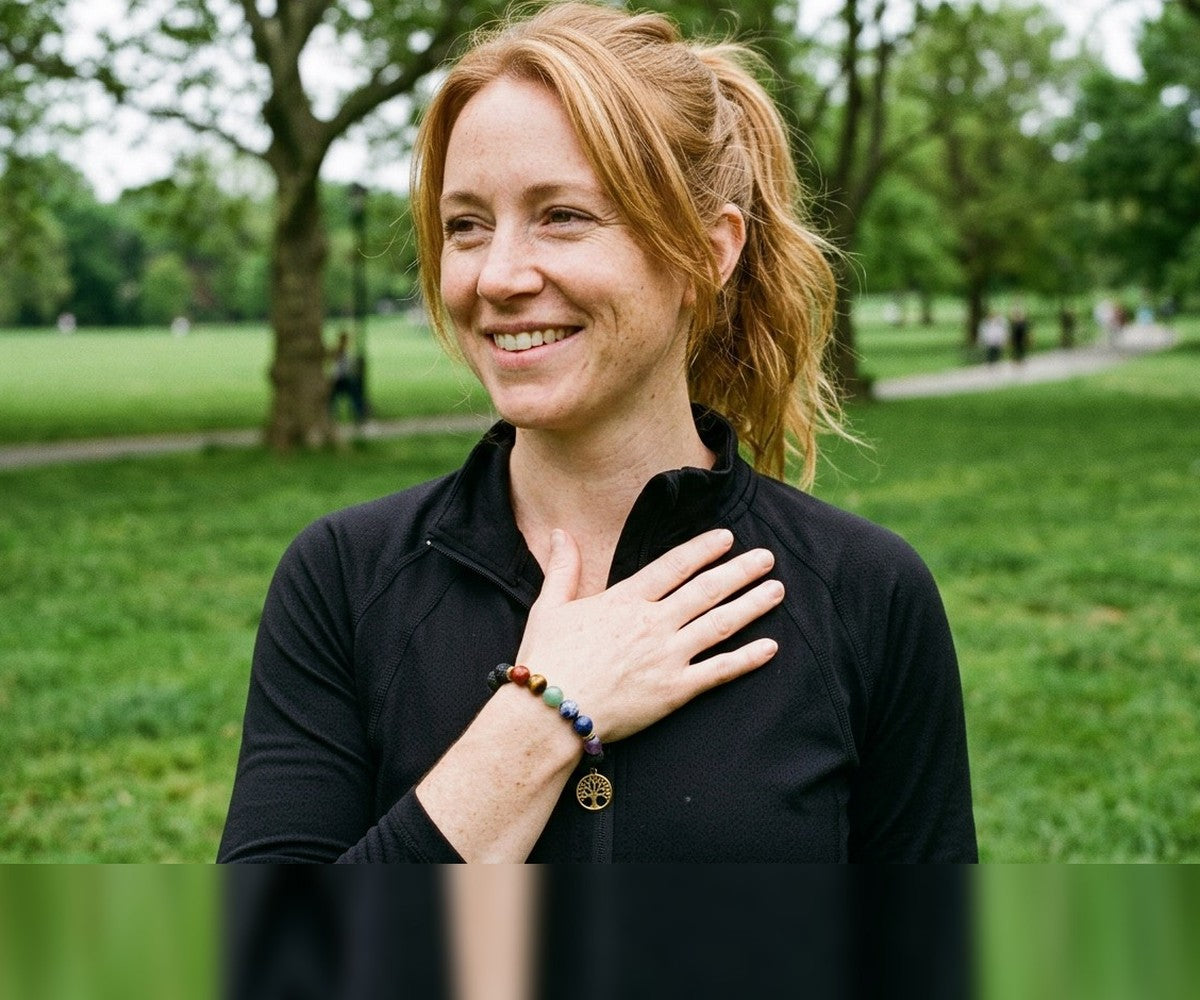 Woman in a London park wearing a LIVLOKO London 7 chakra crystal bracelet with a gold tree of life charm