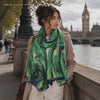 Woman wearing the LIVLOKO London peacock feather green satin scarf by the Thames in London