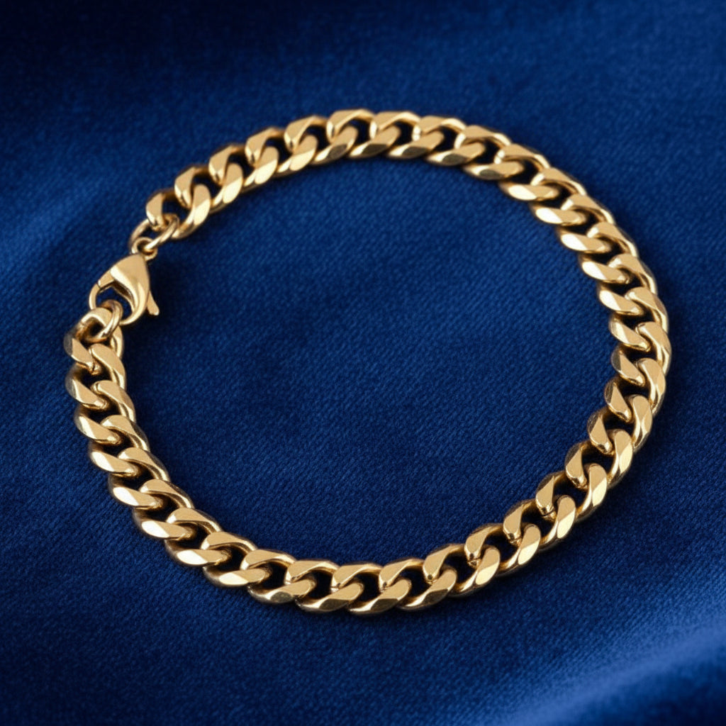 Close-up of polished gold curb chain bracelet laid on dark blue fabric