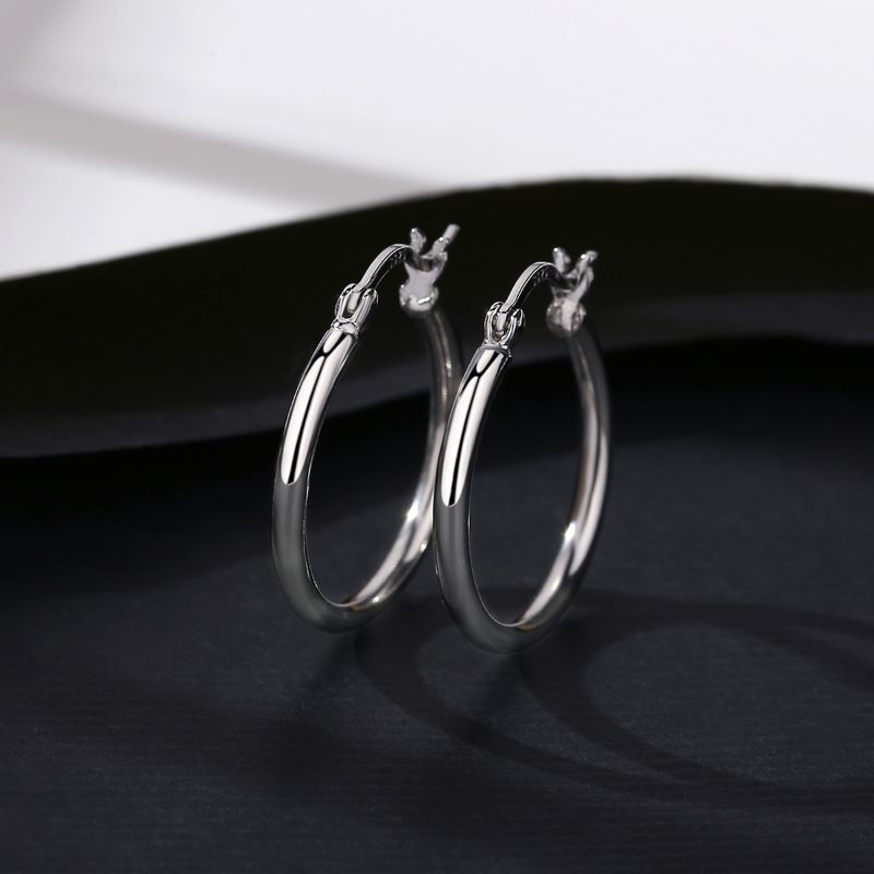 plain Silver Earring placed on black surface