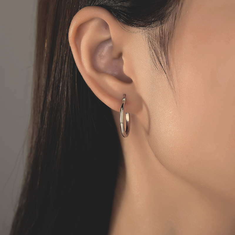 image of woman's ear wearing plain Silver Earring